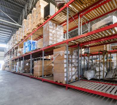 Industrial warehouse interior with stacked steel pallets and goods on metal racks