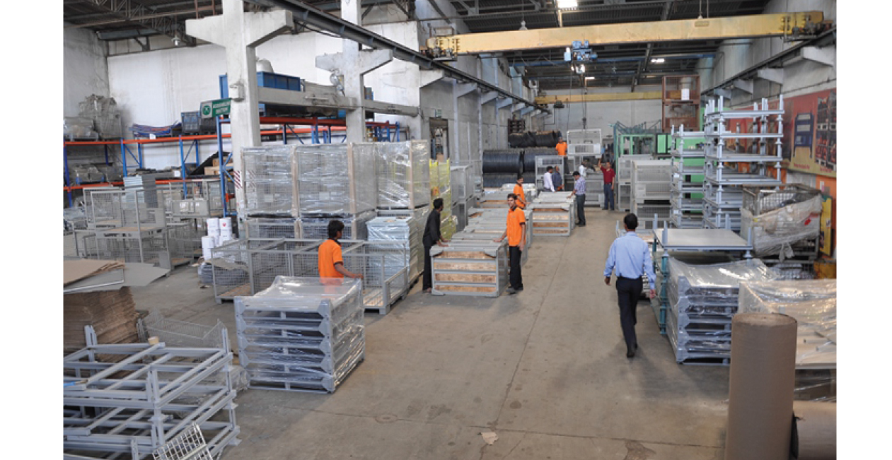 Assembly area at Mekins Industries showing workers assembling metal pallets and cages