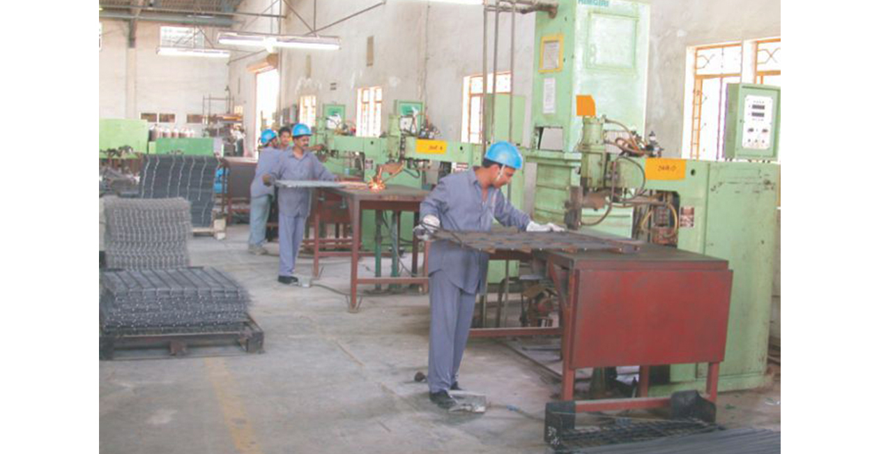 Factory workers operating manual spot welding machines in the production area