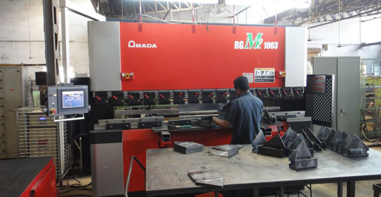 Technician operating CNC bending machine Amada Japan inside manufacturing facility at Mekins Industries